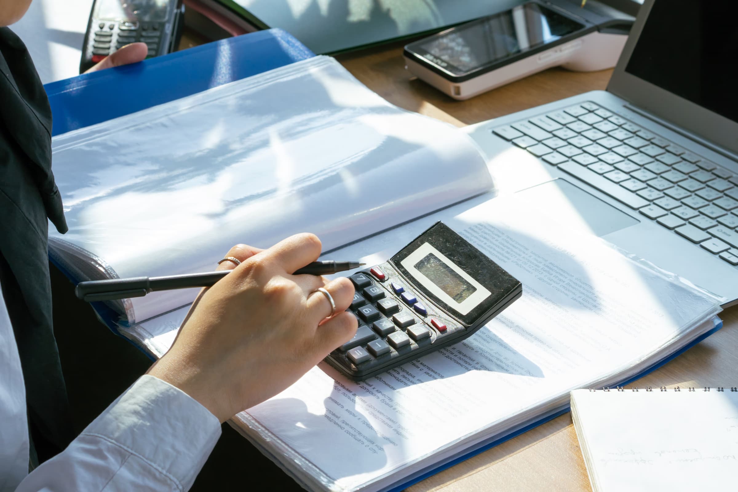 Comptable vérifiant des documents avec une calculatrice à côté d'un ordinateur portable