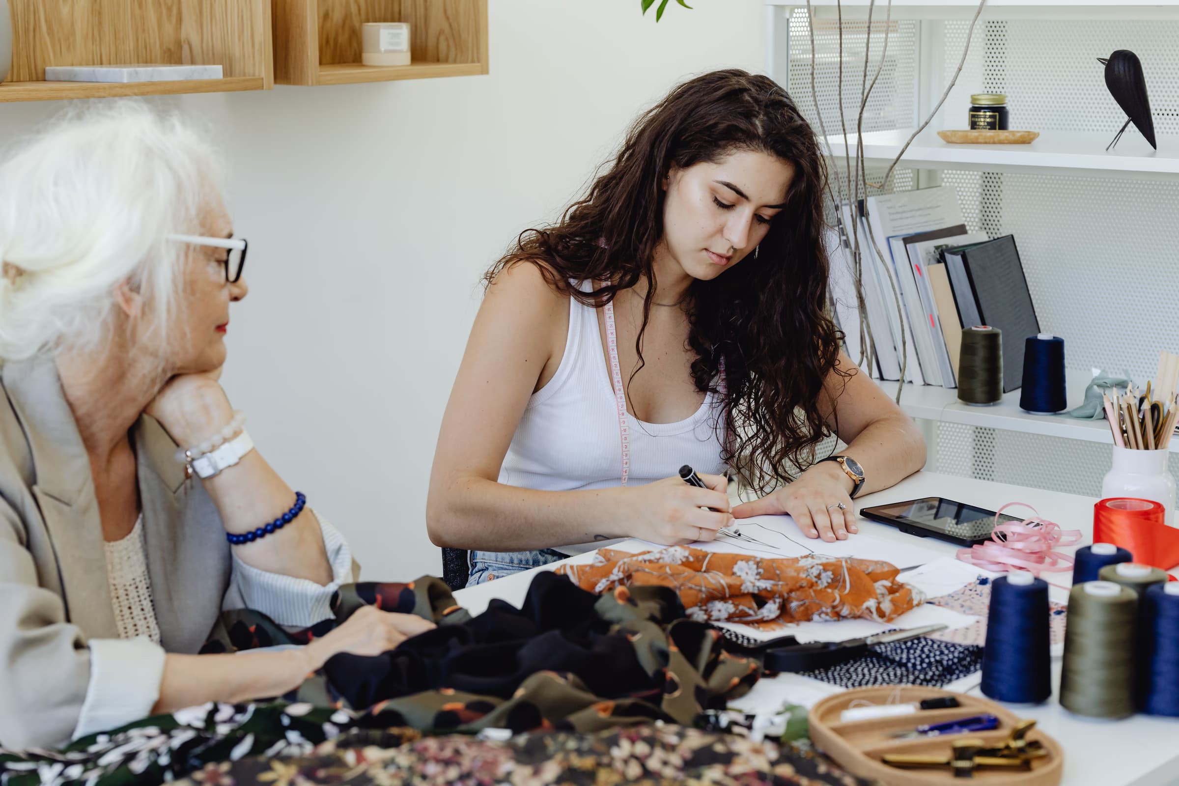 Jeune entrepreneuse de mode travaillant sur sa collection avec un accompagnateur expérimenté